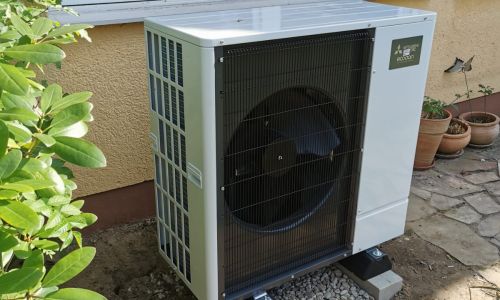 Mitsubishi Ecodan Wärmepumpen Außeneinheit auf Betonfundament vor Hauswand unter Fenster.