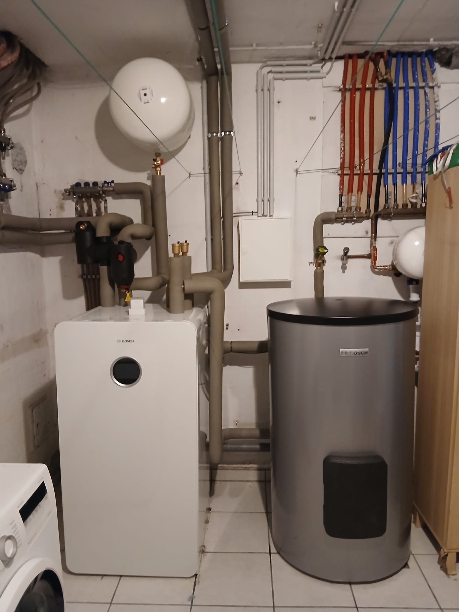 Innenanlage einer Bosch Wärmepumpe mit gut strukturierter Rohrleitung in einem Keller.