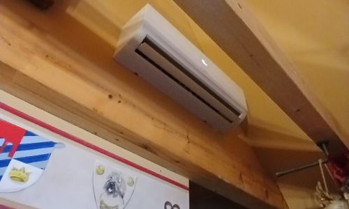 Bosch Klimainnengerät unter Holzbalkendecke montiert, positioniert über einer dekorierten Innenwand.