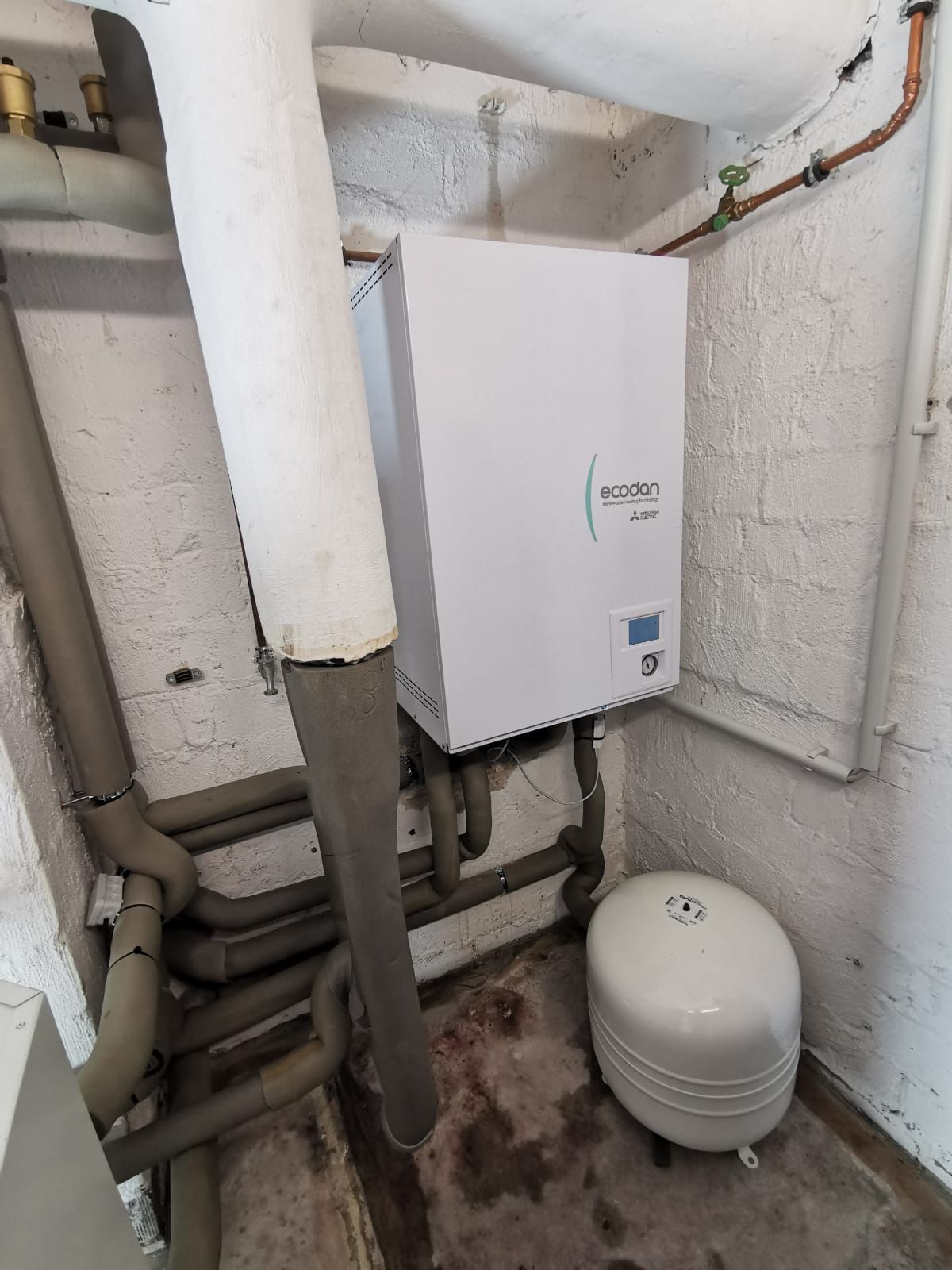 Kellerraum mit Ecodan Inneneinheit, Ausdehnungsgefäß und gedämmten Heizungsrohren.