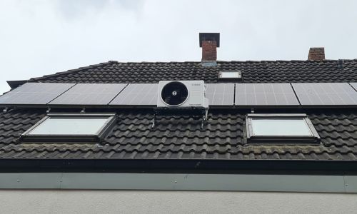 Bosch-Klimaanlage auf Hausdach montiert, eingebettet zwischen Photovoltaik-Modulen und Dachfenstern auf dunkler Ziegeldeckung.
