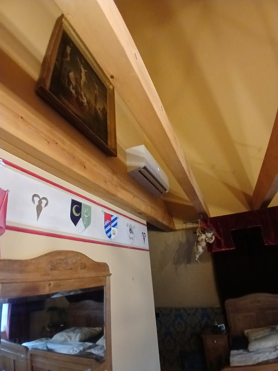 Schlafzimmer mit Bosch Klimainnengerät unter Dachschräge, sichtbar neben Holzbalken.