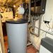 Technikraum mit Pufferspeicher, Wandgerät, zwei Ausdehnungsgefäßen und zahlreichen Rohrverbindungen.