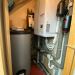 Ecodan-Wärmepumpenmodul an Wand mit Pufferspeicher, Isolierungen und aufliegenden Bedienungsanleitungen.